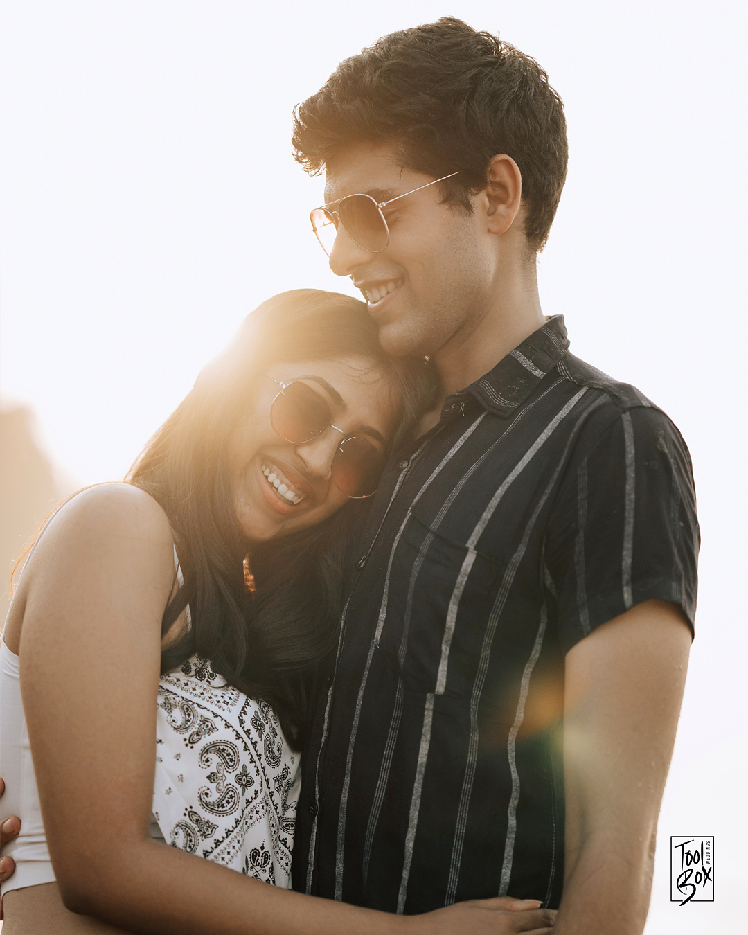 Dipti and Akash laughing together in the evening sun by the sea