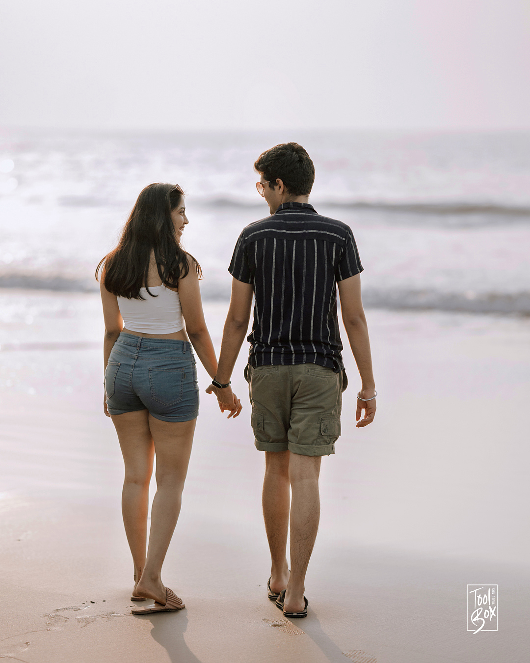 Dipti and Akash walking hand in hand along the shore