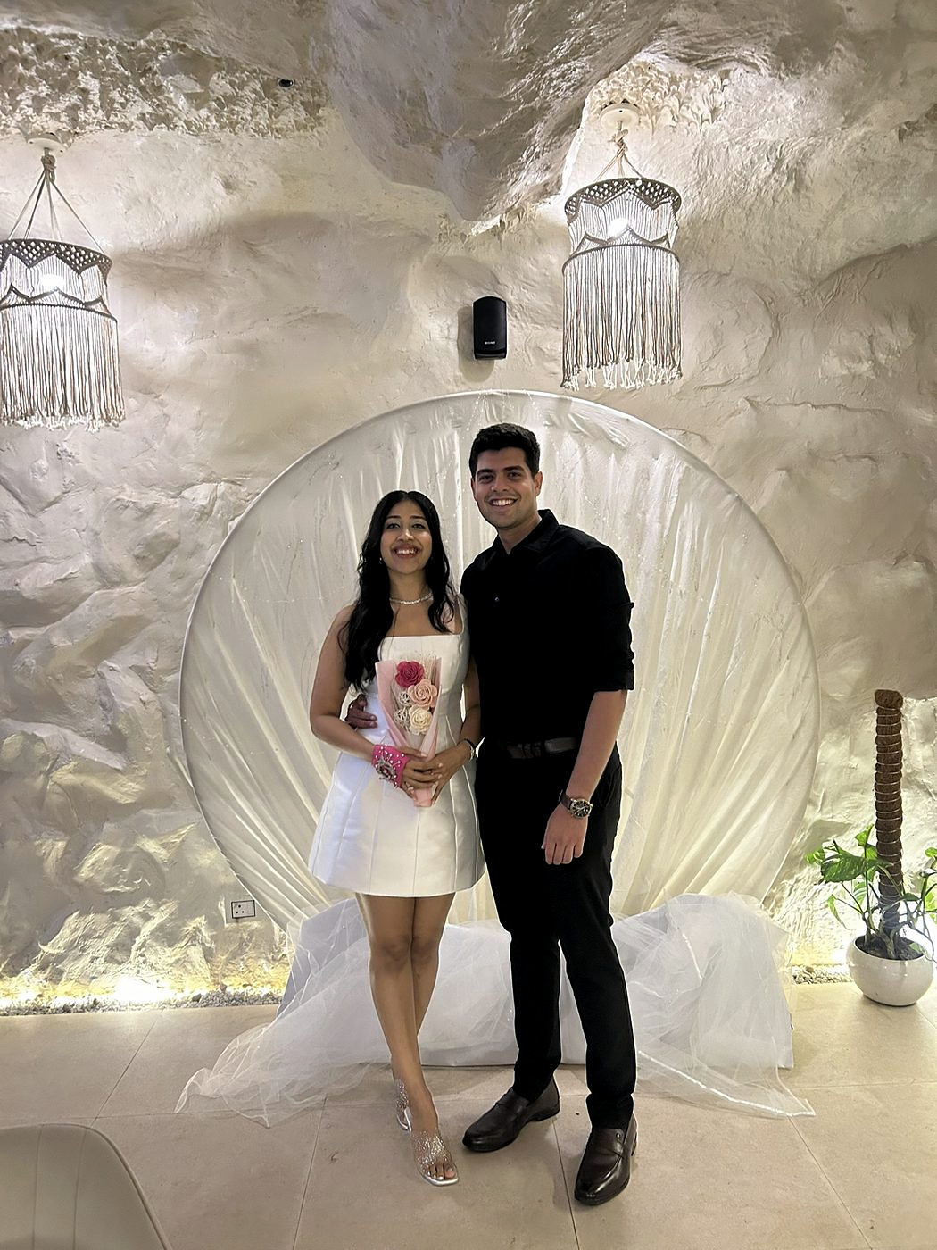 At a white-themed celebration, Dipti holding a bouquet